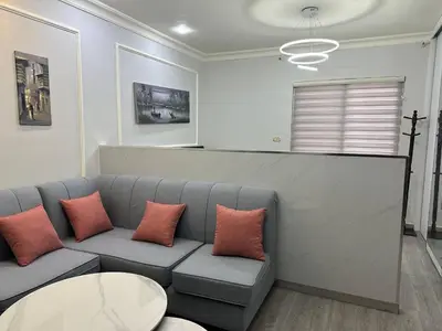 a living room with a gray couch with orange pillows at استوديو الجاردنز gardens studio 319 in Al Jafr