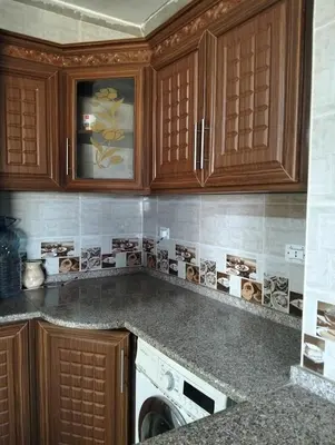 a kitchen with wooden cabinets and a washing machine at ام الينابيع عجلون in Ajloun