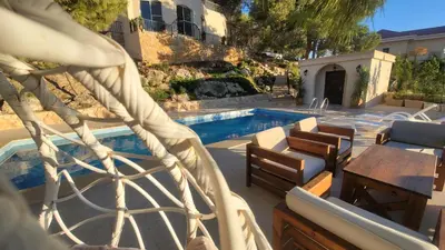 a swimming pool with chairs and a table next to a house at Romana in Ar Rummān