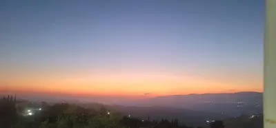 a sunset over a city with mountains in the background at Romana in Ar Rummān
