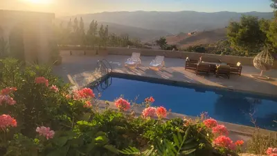 a swimming pool with a table and chairs and flowers at Romana in Ar Rummān
