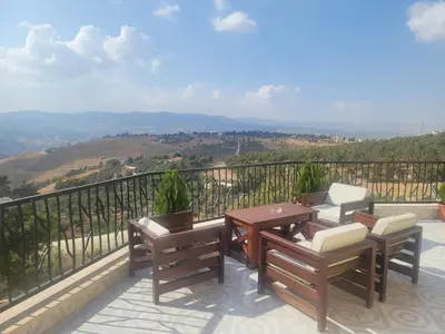 a balcony with a table and chairs and a view at Romana in Ar Rummān