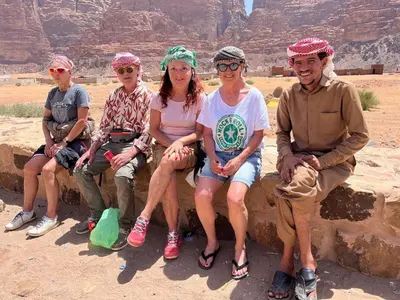 a group of people sitting on a wall in the desert at Adventure Nights Camp in Wadi Rum