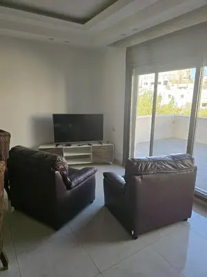 a living room with two leather chairs and a flat screen tv at Le Jardin in Madaba