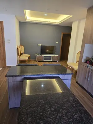 a living room with a tv and a living room with a table at Le Jardin in Madaba