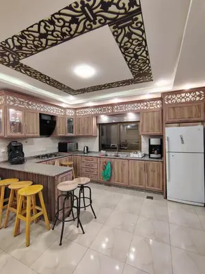a kitchen with wooden cabinets and a white refrigerator at Janna2Villa in Tall al Misţāḩ
