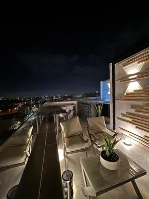 a balcony with chairs and a table at night at Luxury Roof-top in Amman