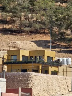 a yellow building in front of a mountain at Sorjat Al Tal Chalet in Umm Tall