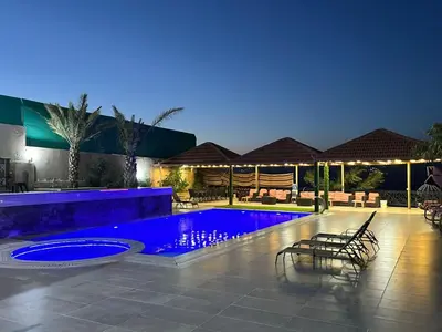 a swimming pool with chairs around it at night at The Royal Chalet in Ath Thukhaynāt