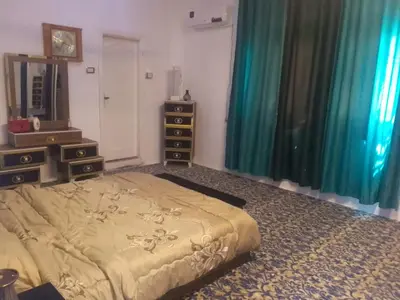 a bedroom with a bed and two dressers and a mirror at الخير شقق مفروشه in Al Jafr
