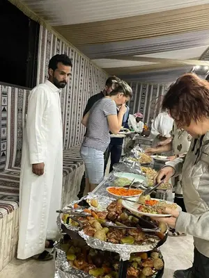 a group of people standing around a buffet line with food at Wahj Ram camp in Aqaba