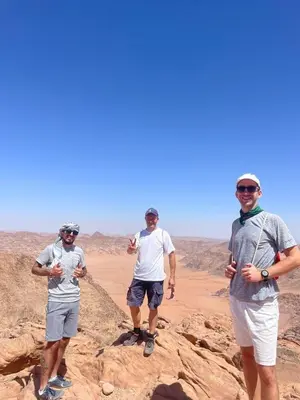 three men standing on a rock in the desert at Wahj Ram camp in Aqaba