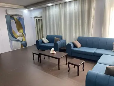 a living room with blue couches and a coffee table at Al Eman Oasis Farm in Jal‘ad