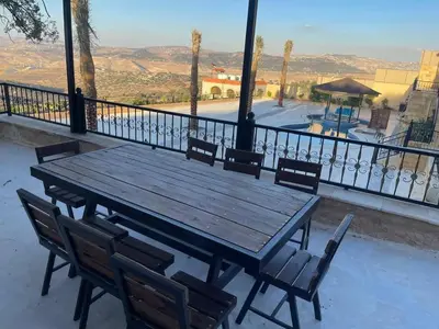 a wooden table and chairs on a balcony at Al Eman Oasis Farm in Jal‘ad