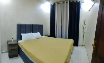 a bedroom with a bed with a blue headboard at Ayla Furnished Apartments in Aqaba