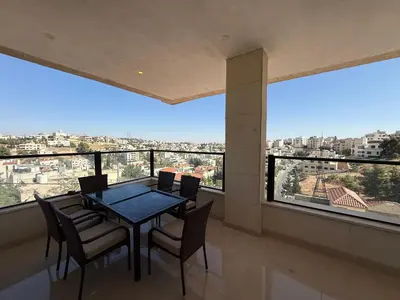 a dining room with a table and chairs and a large window at Dabouq 3BR condo in Amman