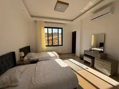 a bedroom with two beds and a desk and a mirror at Dabouq 3BR condo in Amman