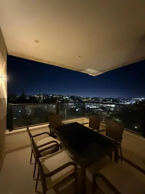 a dining table and chairs on a balcony with a view at Dabouq 3BR condo in Amman