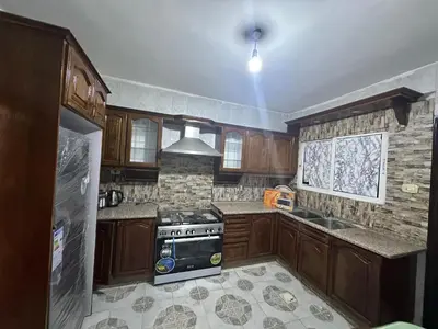 a kitchen with wooden cabinets and a stove top oven at Beautiful apartment in Irbid