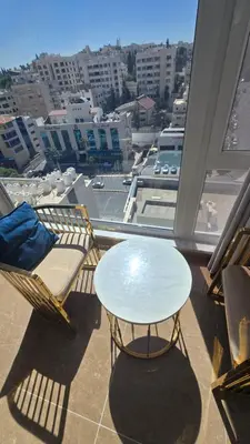 a table and chairs on a balcony with a view of a city at Janty Apartments in Amman