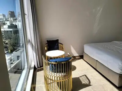 a bedroom with a bed and a table and a chair at Janty Apartments in Amman