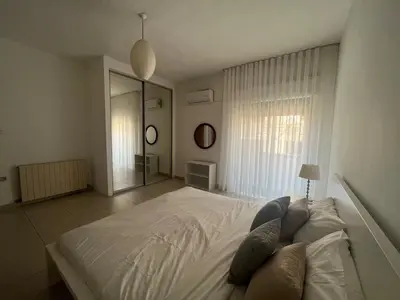 a bedroom with a large bed and a large window at Newly refurbished 2-bedroom flat in a compound in Amman