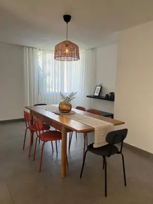 a dining room table with chairs and a pendant light at Newly refurbished 2-bedroom flat in a compound in Amman
