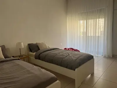 a bedroom with two beds and a window at Newly refurbished 2-bedroom flat in a compound in Amman