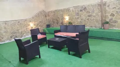 a room with a table and chairs and a green floor at شاليهات تلال اشتفينا in Ajloun