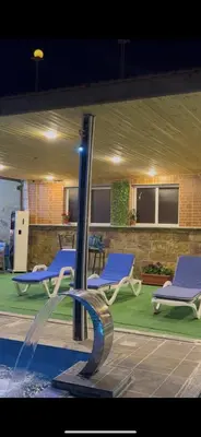 a pool with blue lounge chairs and a fountain at شاليهات تلال اشتفينا in Ajloun