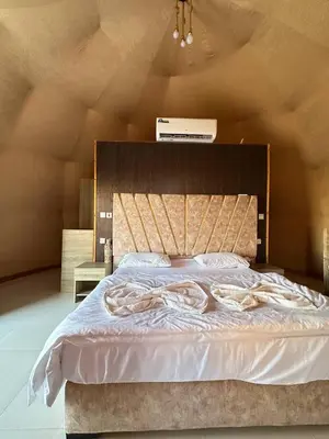 a bedroom with a large bed with white sheets at Camp Imran Khan Wadi Rum in Aqaba