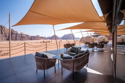 a patio with a table and chairs and an umbrella at Terra Nova Camp in Wadi Rum