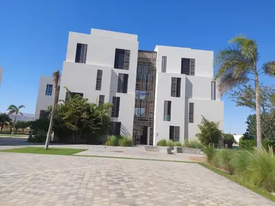 a white building with black shutters on a street at Brand new modern apartment in Ayla Golf residence in Aqaba