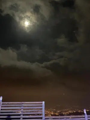 a bench under a cloudy sky with the moon at شاليه بانا جرش in Jerash