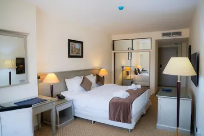 a hotel room with a bed and a desk and mirror at Armada Avenue Hotel Amman in Amman