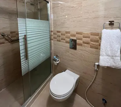 a bathroom with a toilet and a glass shower at Mass Plaza Hotel in Aqaba