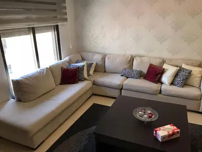 a living room with a white couch and a table at Peaceful apartment in Amman 7th Circle near Cozmo in Amman
