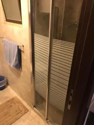 a shower with a glass door in a bathroom at Peaceful apartment in Amman 7th Circle near Cozmo in Amman