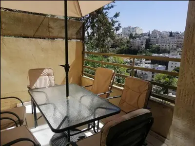 a table and chairs on a balcony with an umbrella at Humble house in Amman