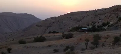 a house on the side of a mountain with the sunset at Tafila-Mataan in Al Jafr