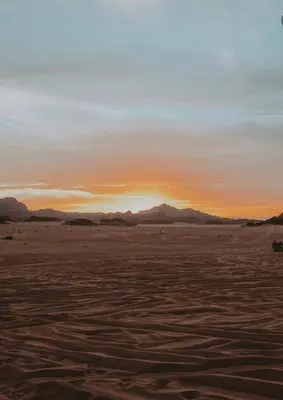 a sunset over the desert with mountains in the background at RUM GALAXY lUXURY CAMP in Disah