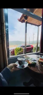 a person holding a cup of coffee on a table at Moose house in Ajloun