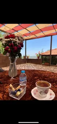 a table with a vase of roses and a cup of coffee at Moose house in Ajloun