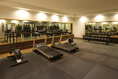 a gym with several tread machines and mirrors at Aroma Hotel in Aqaba