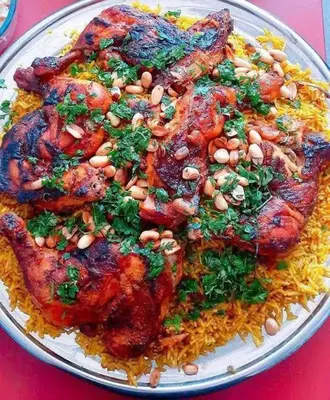 a plate of food with chicken and rice on a table at يرموك هاوس in Aş Şarīḩ