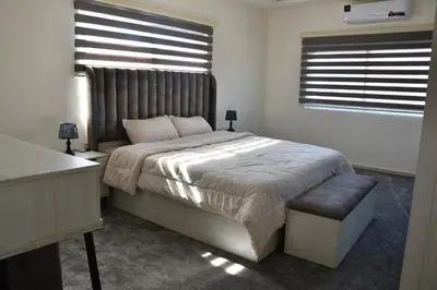 a bedroom with a large bed and two windows at Furnished Apartment شقة مفروشة in Irbid