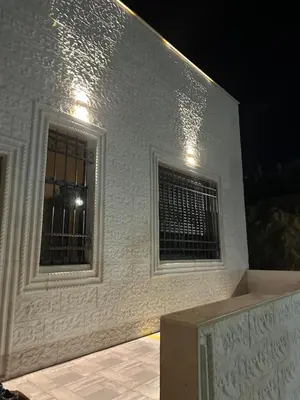 a white building with two windows and a fence at Hassan villa in Sākib