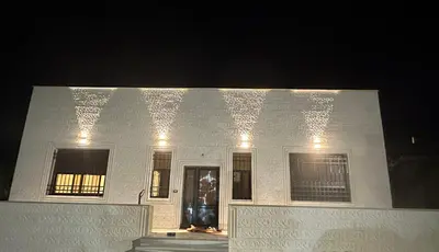 a white building with lights on it at night at Hassan
