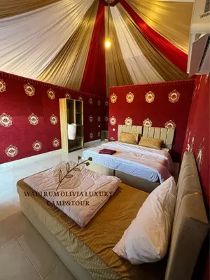 two beds in a room with red and gold walls at WADI RUM OLIVIA lUXURY CAMP & TOUR in Wadi Rum