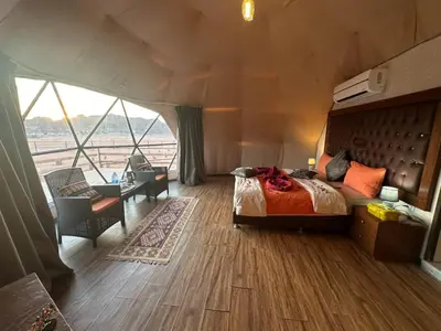 a bedroom with a bed and a large window at Luxury diamond camp in Wadi Rum